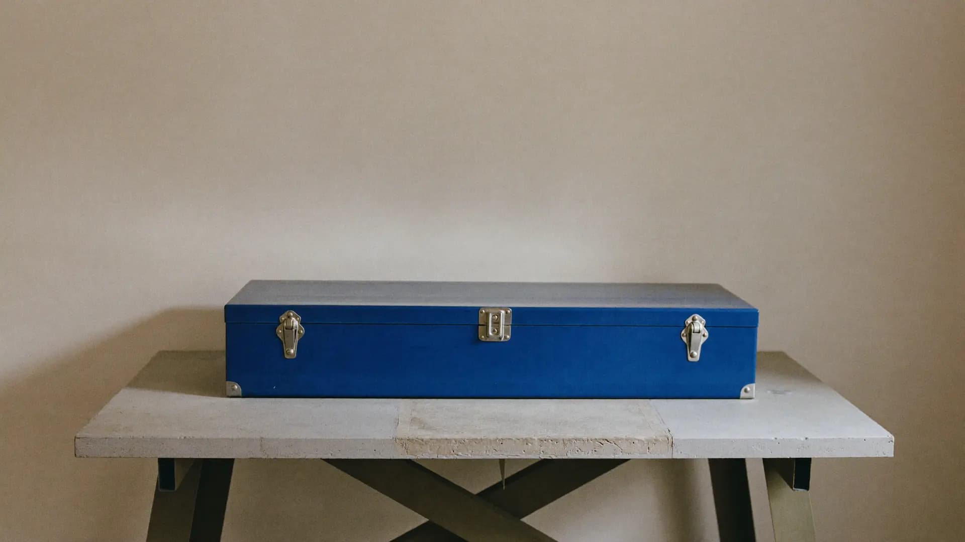 A closed blue toolbox on a concrete workbench
