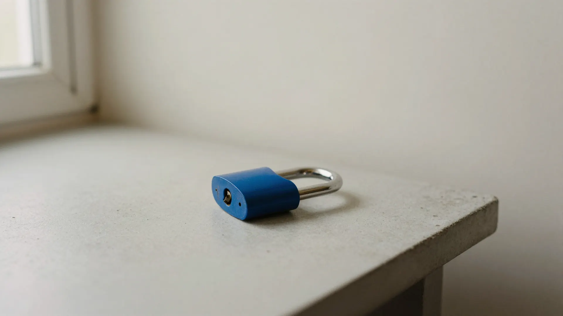 A blue padlock on a concrete workbench